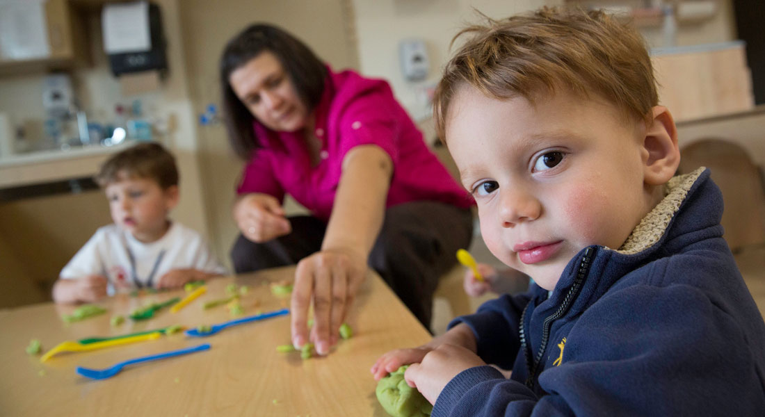 preschoolers and teacher playing with play-doh