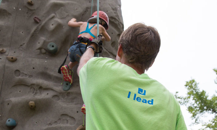 camp counselor belaying camper on rock wall