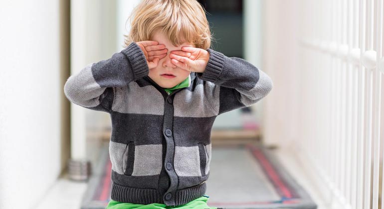 little boy covering eyes with hands