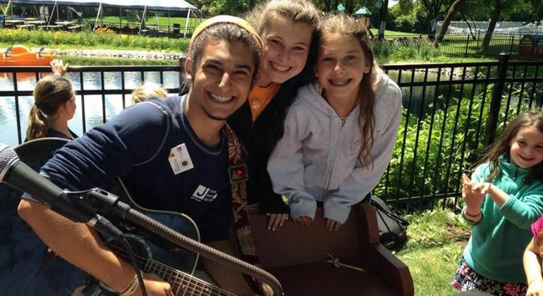 counselor holding guitar smiling with campers