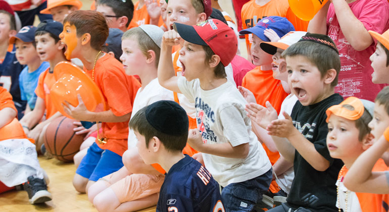 boy campers clapping and cheering at basketball game