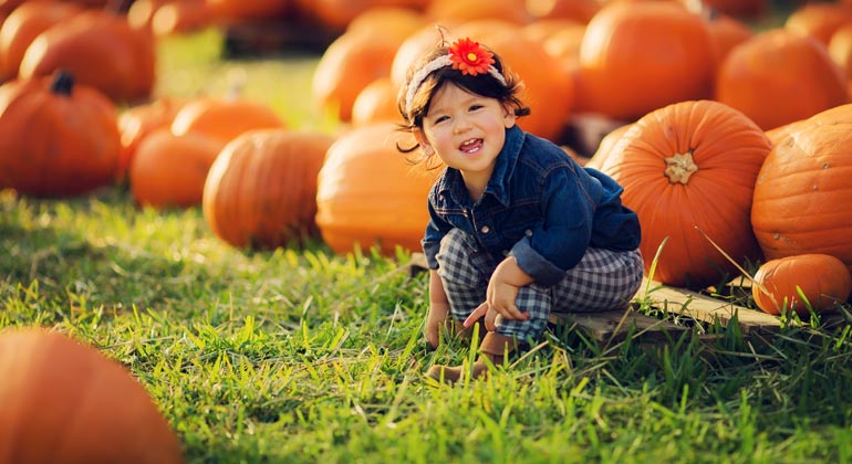 little girl smiling at pumpkin patch