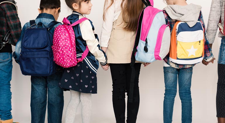 kids with backpacks holding hands